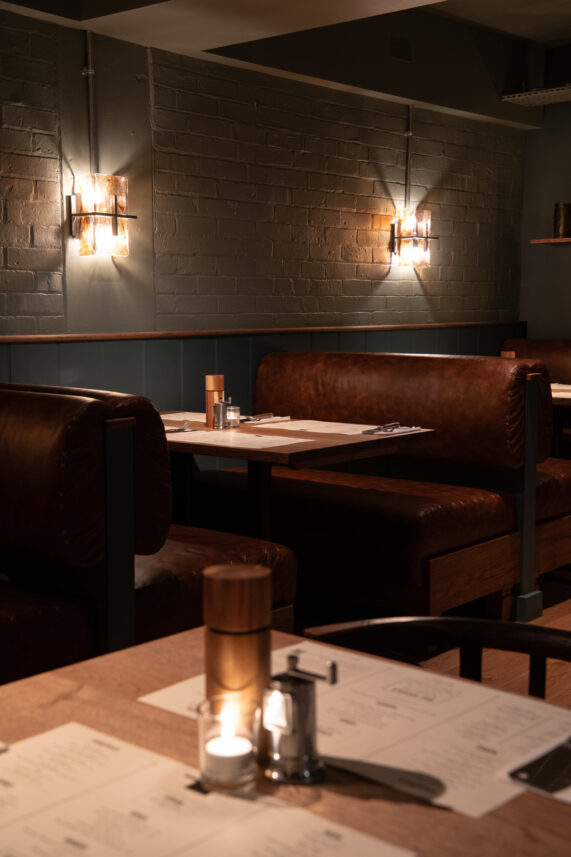 Leather banquette booths, painted brick wall, ambient wall lights