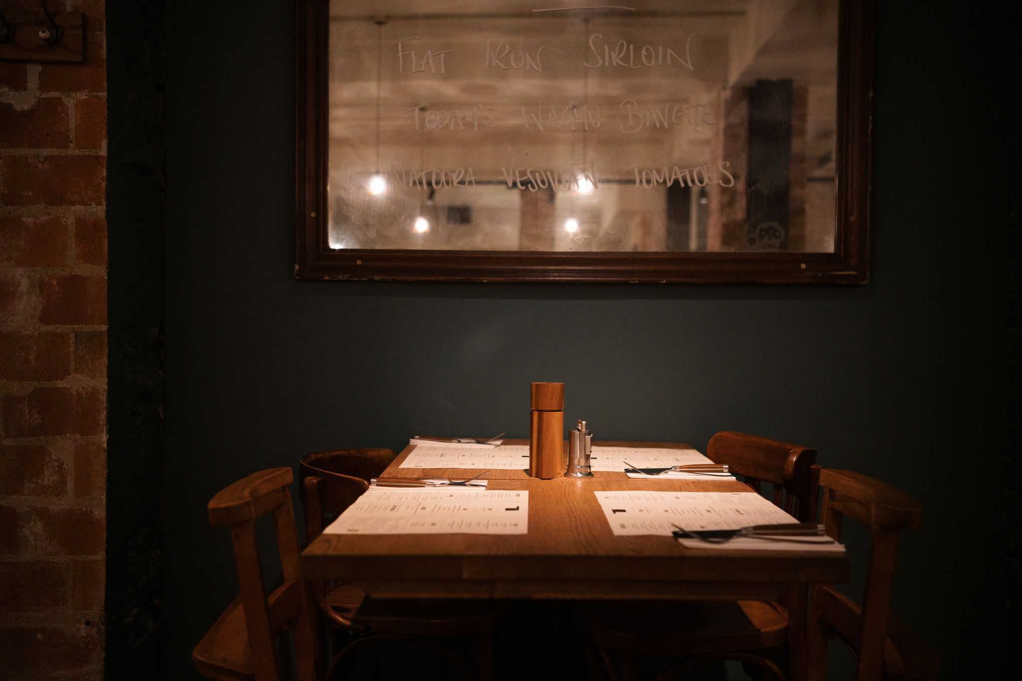 Table setting with mirror with menu options written on it, cosy lighting.