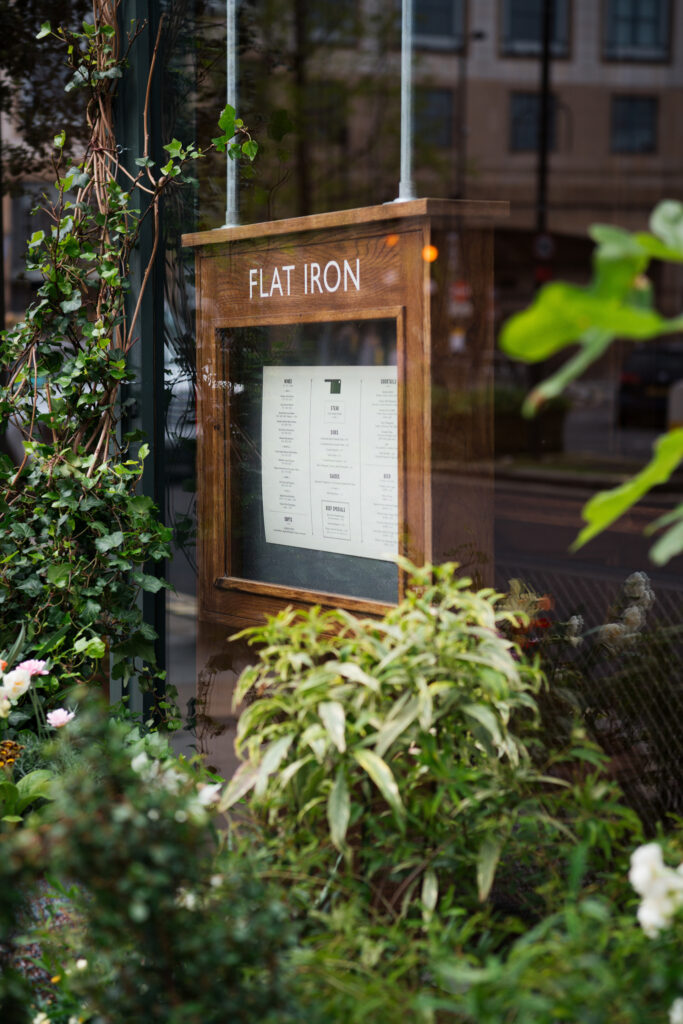 Flat iron hammersmith outside menu surrounded by lots of plants.