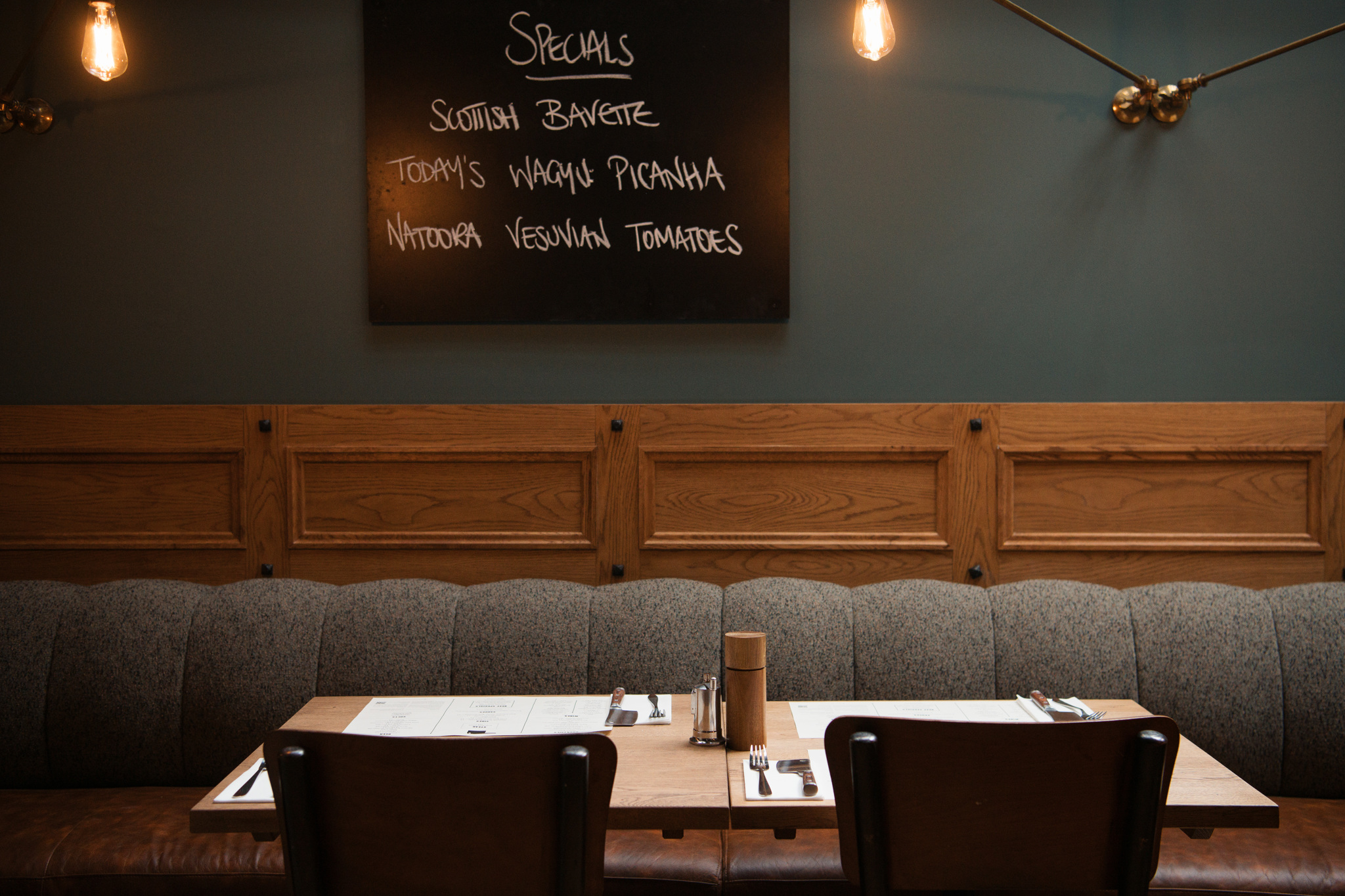 Grey Banquettes with table, blackboard with menu on the wall.