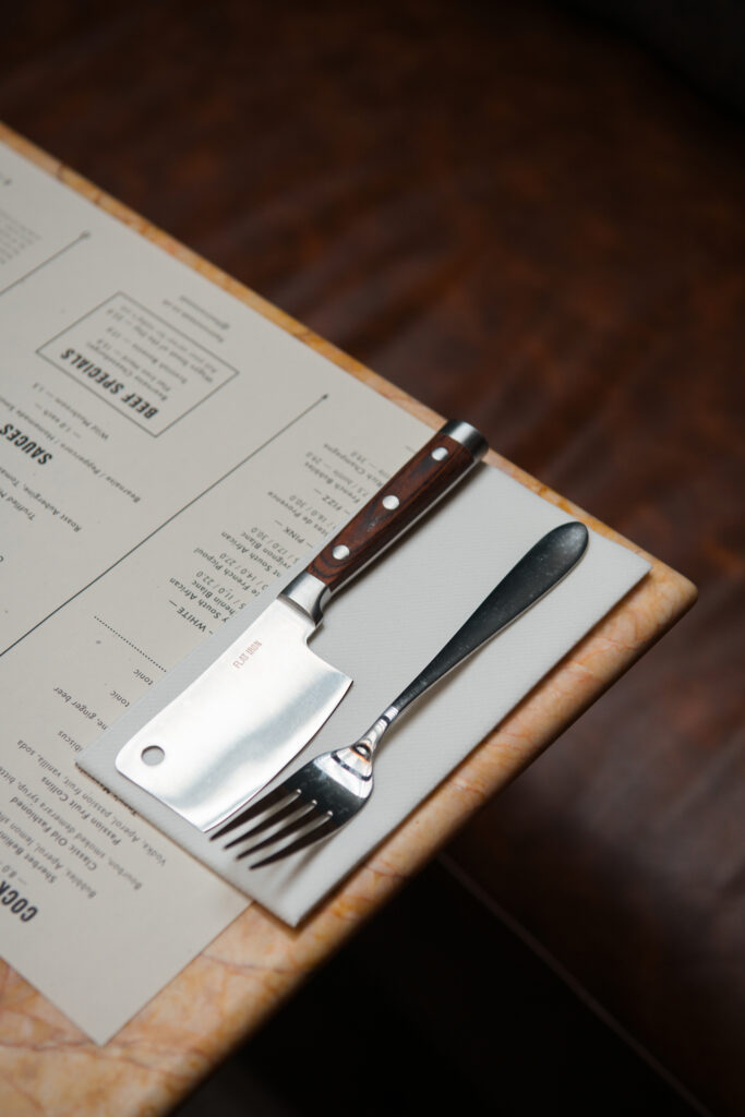 Resturant table setting with Flat Iron cleaver, fork and menu.