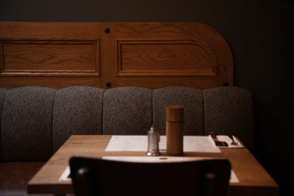 wood banquette with textured upholstery, wood table with menu
